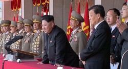 Kim Jong-Un profitant du défilé aux côtés de ses généraux et d'un représentant de la Chine. 
