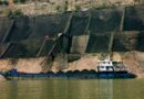 Au premier plan, une barge de transport de charbon en Chine. Derrière, sont visibles de grandes quantités extraites.