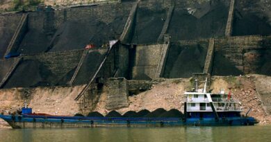 Au premier plan, une barge de transport de charbon en Chine. Derrière, sont visibles de grandes quantités extraites.