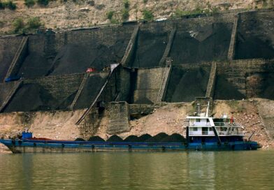 Au premier plan, une barge de transport de charbon en Chine. Derrière, sont visibles de grandes quantités extraites.