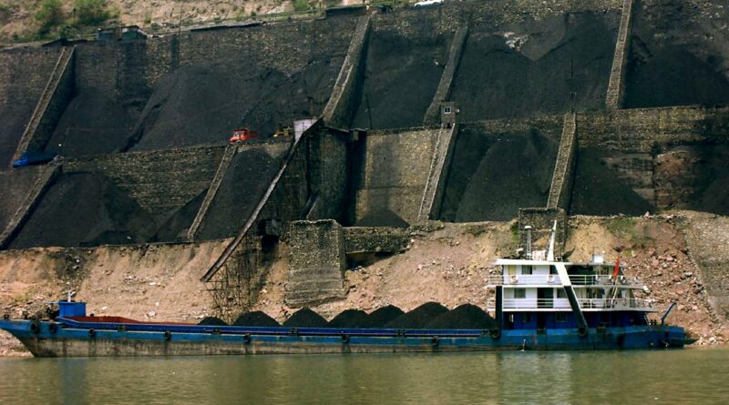 Au premier plan, une barge de transport de charbon en Chine. Derrière, sont visibles de grandes quantités extraites.